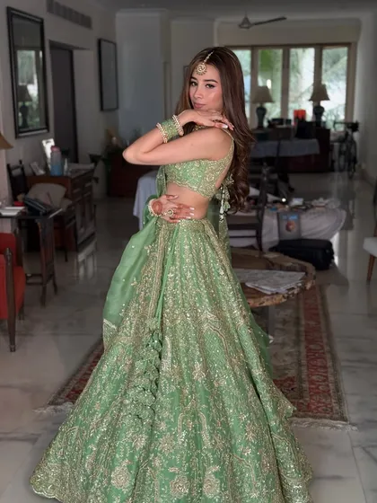 A full-length shot of this stunning mint green lehenga for a Mehendi. The makeup is minimal and dewy, with a simple maang tikka to complete the look.