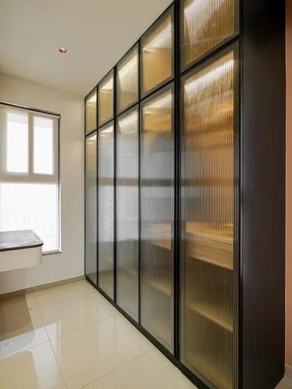 A modern wardrobe with fluted glass panels and internal lighting, offering a sleek storage solution.