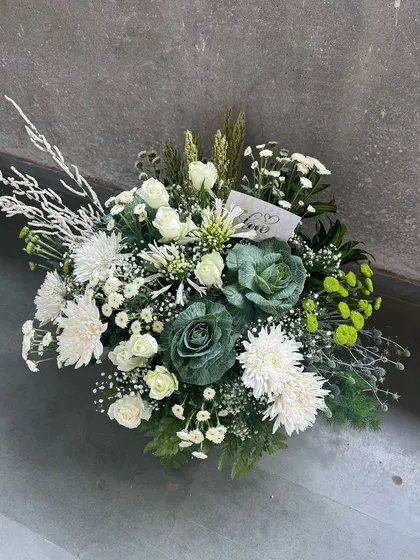 A beautiful bouquet-style gift topper, featuring a mix of white chrysanthemums and ornamental kale. This showcases our expertise in using unique and trendy florals to elevate our gift presentations.