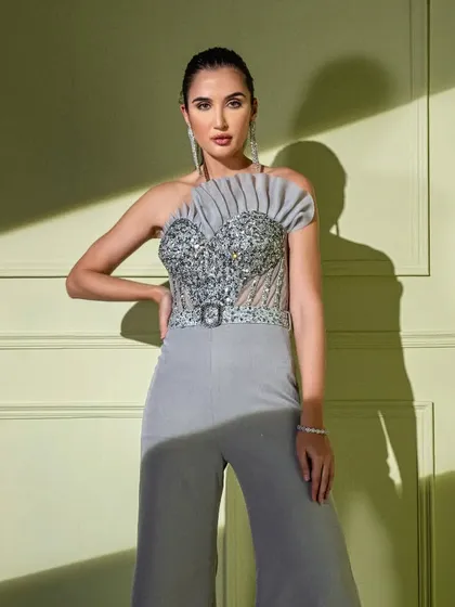 A statement in grey, this jumpsuit features a fully embellished corset top with a unique pleated fan detail on one shoulder. The belted waist and wide-leg trousers create a chic, contemporary silhouette.