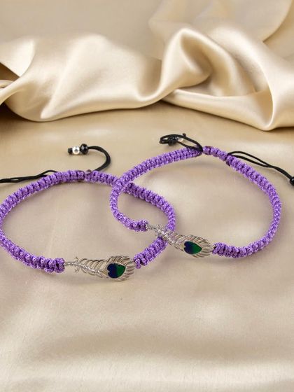 A pair of purple woven bracelets with a silver peacock feather charm.