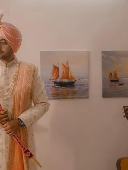 A portrait of the Sikh groom, looking regal in his sherwani and turban, holding the kirpan as he prepares for his wedding.