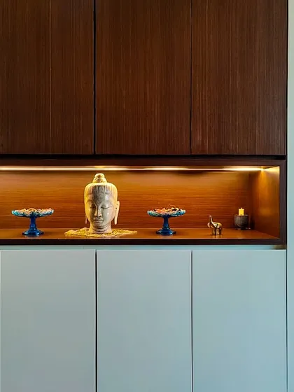 A minimalist pooja or meditation space within the Jesrani Residence. The design uses clean lines, concealed lighting, and a simple wooden cabinet to create a tranquil and spiritual corner that feels integrated with the home's modern aesthetic.