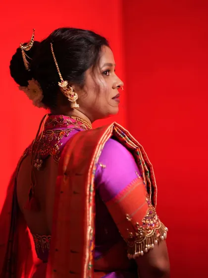 A view of the bride's back, highlighting the detailed blouse design and the classic bridal bun with hair jewelry.