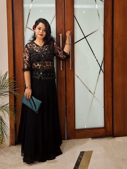 This full-length shot of the black lace outfit highlights its elegant silhouette. A contrasting clutch and a flower in the hair add personal touches that complete the look.