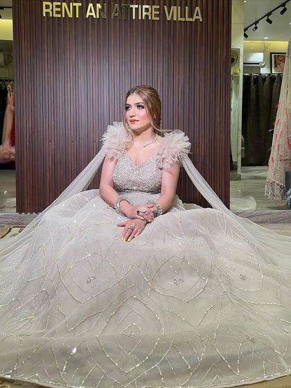 Another shot of the beige ball gown with a feathered cape, this time in front of my studio's branded wall. This dress combines classic elegance with high-fashion details.