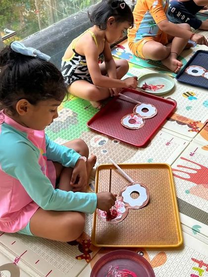 After some water fun, it's time for more art. Here, the children are painting donut cutouts, still in their swimsuits and ready for more play.