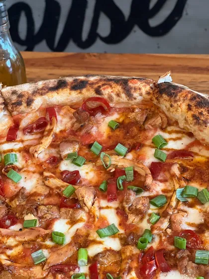 A close-up of the Adobo Chicken pizza, showing the tender chicken and fresh green onions.