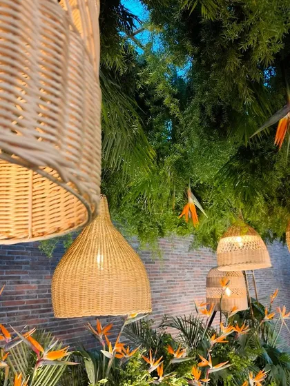 Another perspective of the cane lanterns, hanging amidst a ceiling of lush greenery. This design element is perfect for bringing a touch of natural, bohemian style to any venue.