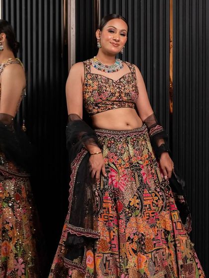 This multi-colored printed lehenga with a black embroidered blouse is a bold and artistic choice for a sangeet or cocktail event. It's a true statement piece from our rental collection.