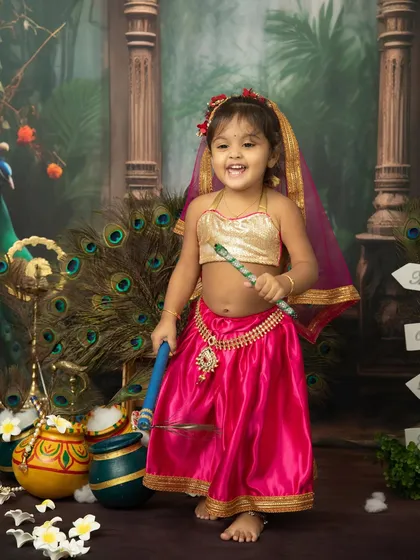 A joyful little Radha ready to play. Her bright pink outfit and happy smile perfectly capture the festive spirit of Janmashtami.