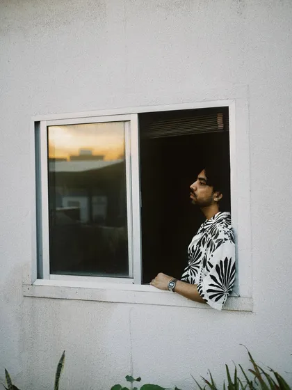 A friend looking out a window at sunset. The warm glow of the sky is reflected in the glass, creating a beautiful, contemplative mood.