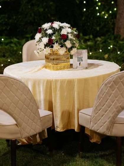 An elegant and simple table setting for the outdoor reception, with a classic floral centerpiece and modern quilted chairs.