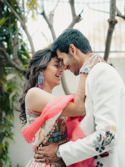 An intimate close-up of a couple, their foreheads touching, sharing a happy and loving moment. This shot highlights their connection and the joy of their pre-wedding celebrations.