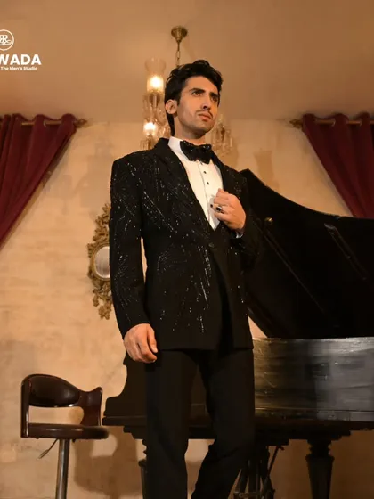 A full-length view of a black sequined tuxedo, showcasing its elegant silhouette against a classic, luxurious backdrop.