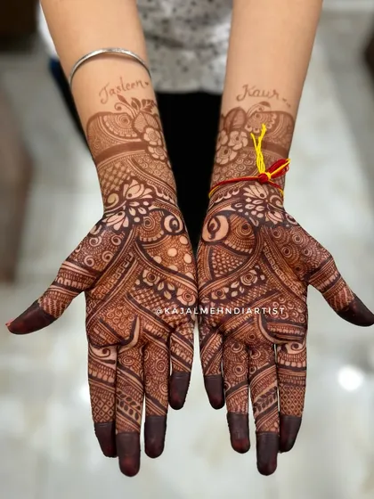 The beautiful, dark stain of a bridal henna design, with the bride's name, Jasleen Kaur, written elegantly on the wrists.