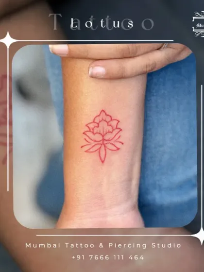 This red ink lotus tattoo on the wrist is a symbol of purity and rebirth. Using colored ink for fine line work can give a traditional symbol a modern and striking appearance.