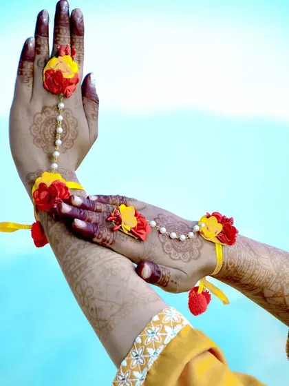 A close-up shot focusing on the beautiful floral hand jewelry (hathphool) and the detailed mehndi art.