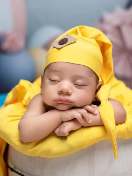 A pop of sunshine yellow in this sweet newborn portrait. The baby is sleeping soundly on top of a white bucket, wrapped in a bright yellow cloth that brings warmth and joy to the image.
