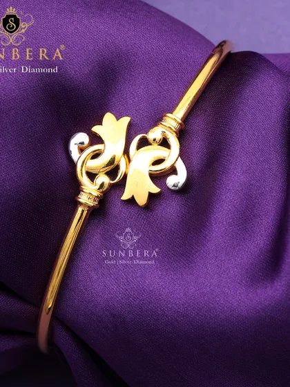 This gold bracelet has a unique and artistic design with abstract floral or leaf-like motifs in a two-tone finish. It’s a statement piece for those who appreciate creative jewellery.