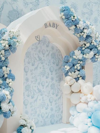 A floral and balloon arch in shades of blue and white, with 'BABY' written in the archway, creating a perfect photo backdrop.