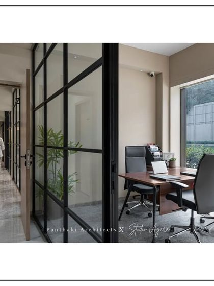 A glimpse into a private meeting room through a glass partition, illustrating how our designs promote a culture of openness and collaboration. A person walking down the corridor adds a sense of life to the space.