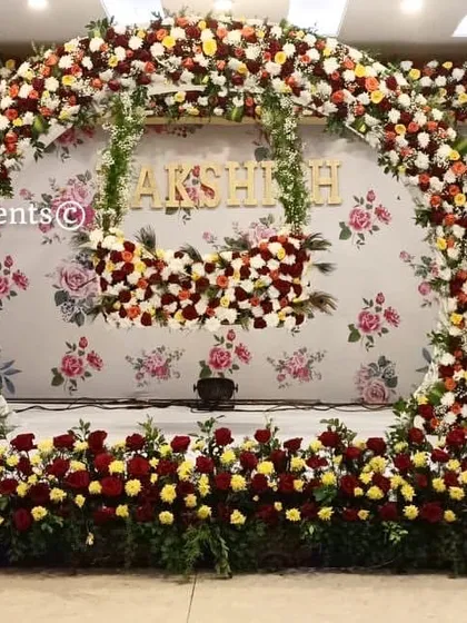 A beautiful floral arch designed for a naming ceremony. The stage is decorated with red and yellow roses, with the baby's name featured in the center for a personalized touch.