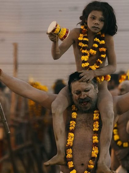 A powerful and tender moment from the Kumbh Mela, as a Naga sadhu carries a young child on his shoulders during a procession. It shows the passing of tradition from one generation to the next.