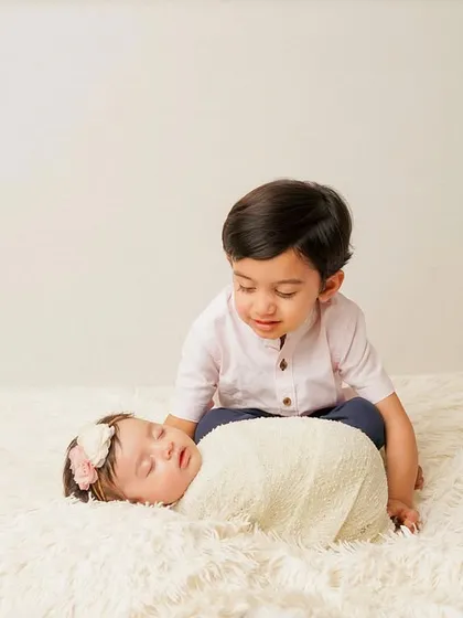 A big brother looking down at his new sibling with a gentle expression. This photo captures the beginning of a beautiful friendship.