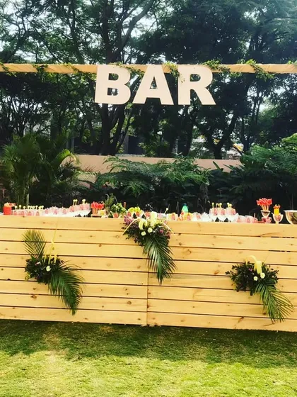 A rustic wooden bar, perfect for an outdoor Haldi ceremony. The natural wood and floral decorations create a beautiful, relaxed setting.
