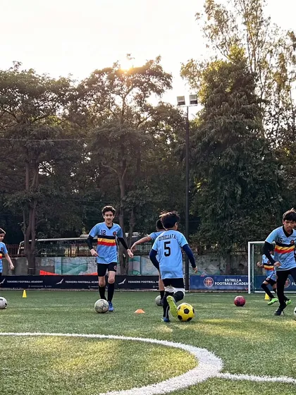 A group of young players focused on a dribbling drill during a sunny evening session. I ensure every player gets comfortable with the ball at their feet, building confidence and control from a young age.