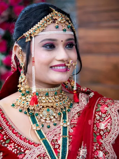 A close-up of bridal beauty. This shot highlights the stunning bridal jewellery and the intricate details of the red lehenga's blouse and dupatta.