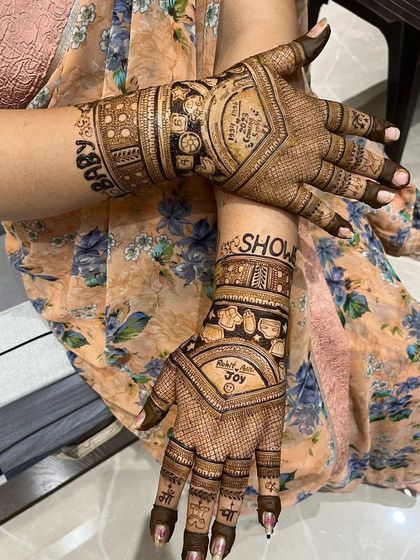 A bold and beautiful baby shower mehndi. The words "Baby" and "Show" are written in large letters on the forearms, with the family name "Joy" and other traditional motifs on the palms.