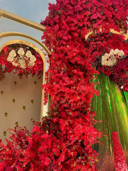 A detail of the floral decor, where a wall of red flowers meets a digital screen, creating a seamless blend of nature and technology.