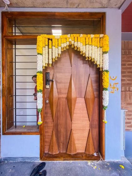 The entrance to the Tripathy home, adorned for the housewarming. The custom wooden door provides a warm welcome, contrasting beautifully with the earthy brickwork.