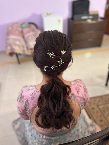 A soft, messy ponytail with a textured crown, adorned with delicate baby's breath. A romantic choice for an engagement or garden party.