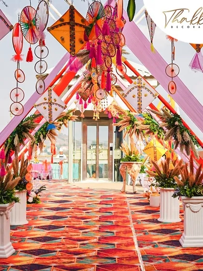A colorful and festive entrance for a kite-themed event. The walkway is decorated with hanging kites and dreamcatchers, creating a vibrant and playful welcome.
