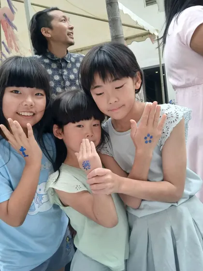 Friends showing off their matching blue glitter tattoos together. Getting body art is a fun group activity that adds a special, memorable touch to any celebration.