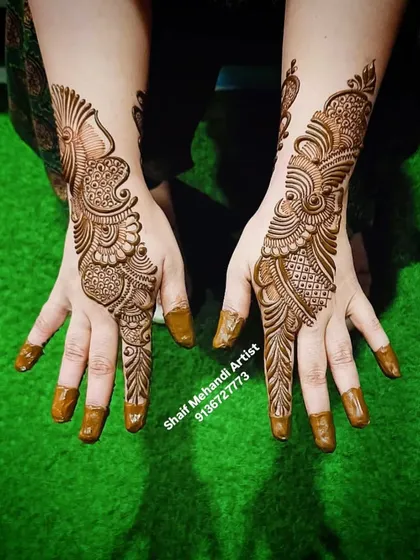 A classic Arabic peacock-style design for the back of the hand, with the henna paste freshly applied.