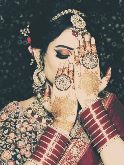 A shy bride portrait, focusing on the beautiful mehendi design on her hands as she covers her face.
