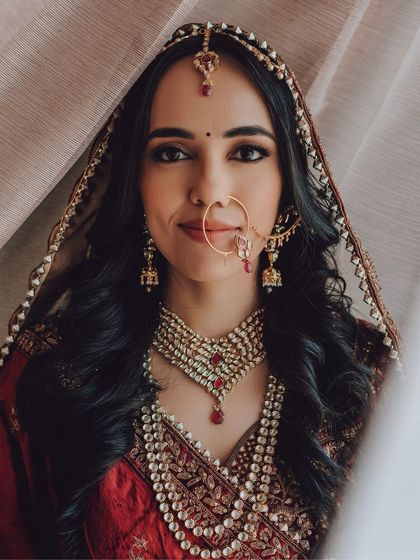 A classic bridal portrait, with the bride looking confidently into the camera, her traditional jewelry and nath on full display.