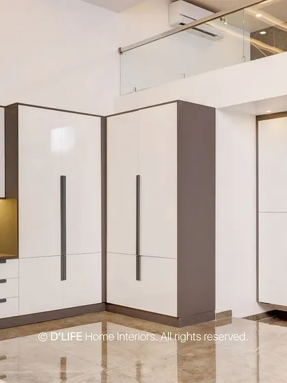 A view of the bedroom's integrated wardrobe and study unit, showcasing a clean, modern design with white and grey finishes that maximize space and light.