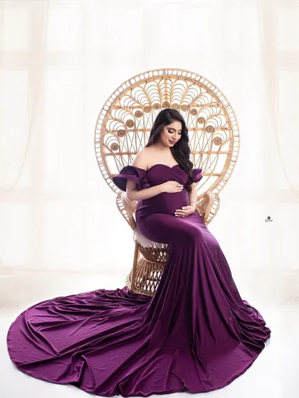 A close-up shot in the peacock chair, focusing on the client's happy expression. The rich purple of the gown adds a touch of luxury to this bohemian-inspired setup.