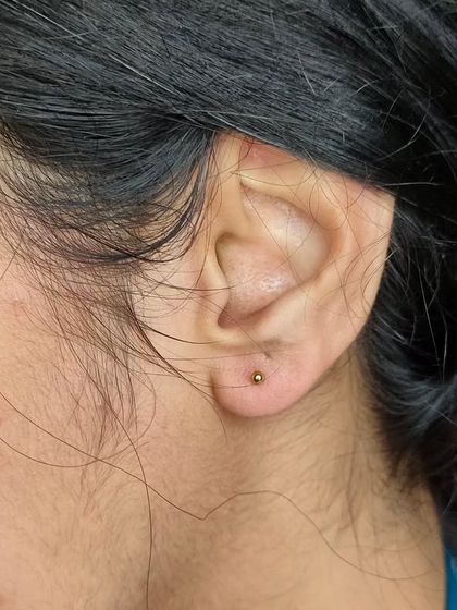 A simple, classic earlobe piercing with a gold-tone stud. We offer a variety of basic and decorative jewelry options for your new piercing.