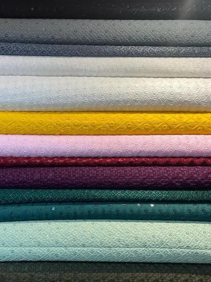 A stack of pure Chikankari fabrics, showcasing the range of colors I offer for bespoke kurtas. This traditional hand-embroidered textile from Lucknow is a popular choice for its elegance and breathability.