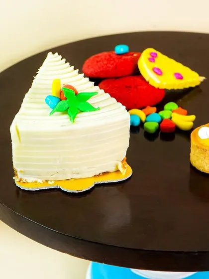 A close-up of a cake slice and an eclair on a decorative cake stand, showcasing bakery items.