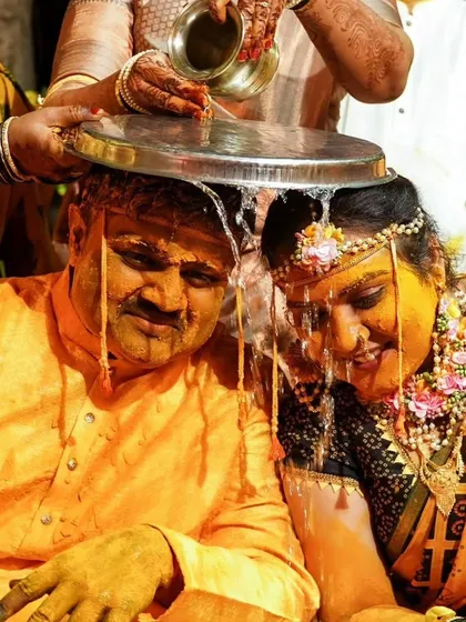A traditional Haldi ritual where water is poured over the couple, symbolizing purification and blessings before their union.