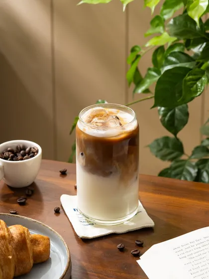 A refreshing iced latte paired with a croissant. A simple, classic breakfast combination shot in beautiful natural light.