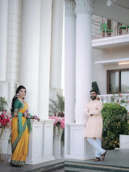 Individual portraits of the bride and groom against grand white pillars. These shots highlight their style and the elegance of their Haldi event.