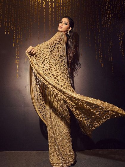 A dramatic and glamorous shot. The makeup is kept clean and elegant to balance the show-stopping gold sequin saree. The focus is on a flawless complexion and defined eyes.
